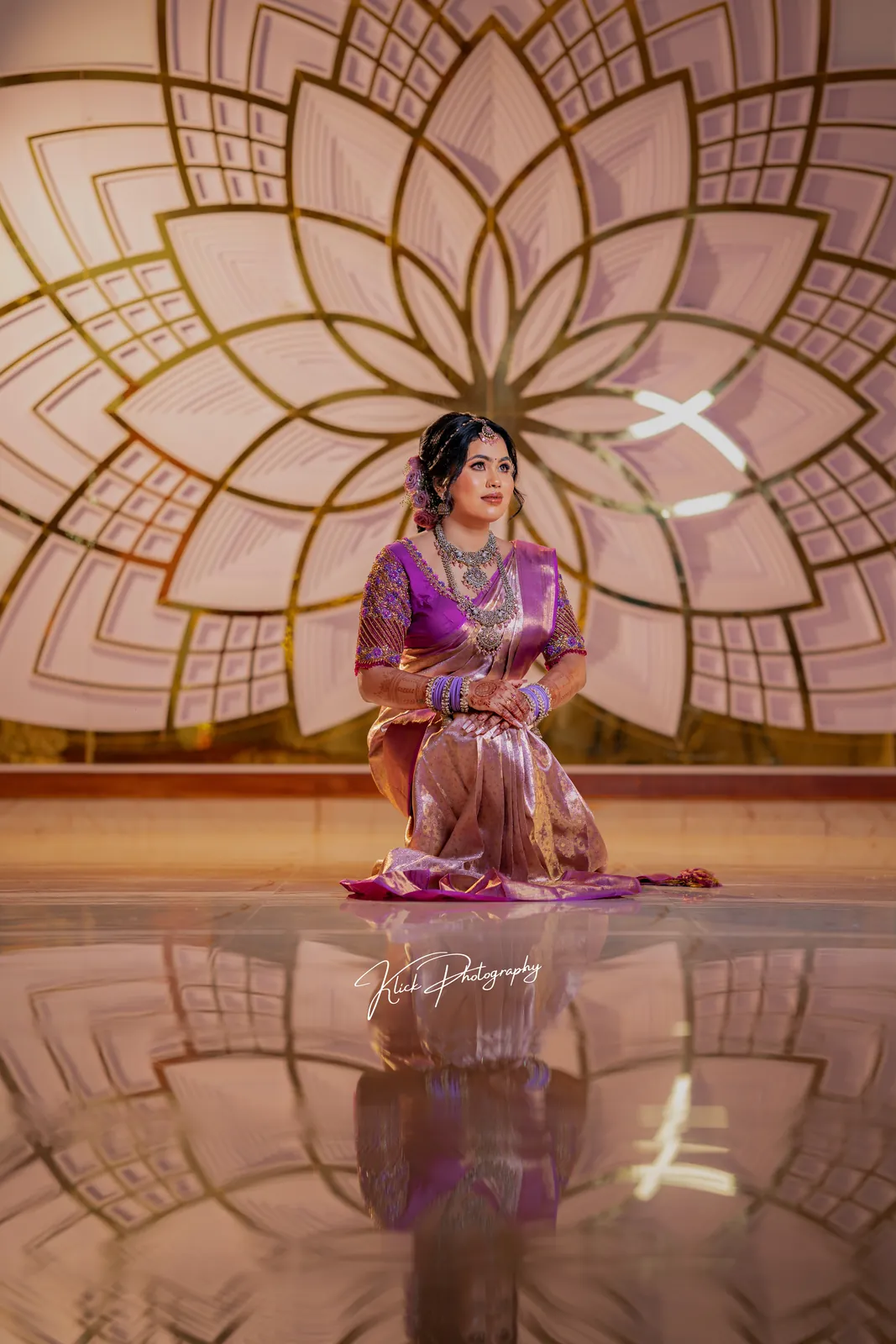 Bride in a purple saree seated on a decorated stage