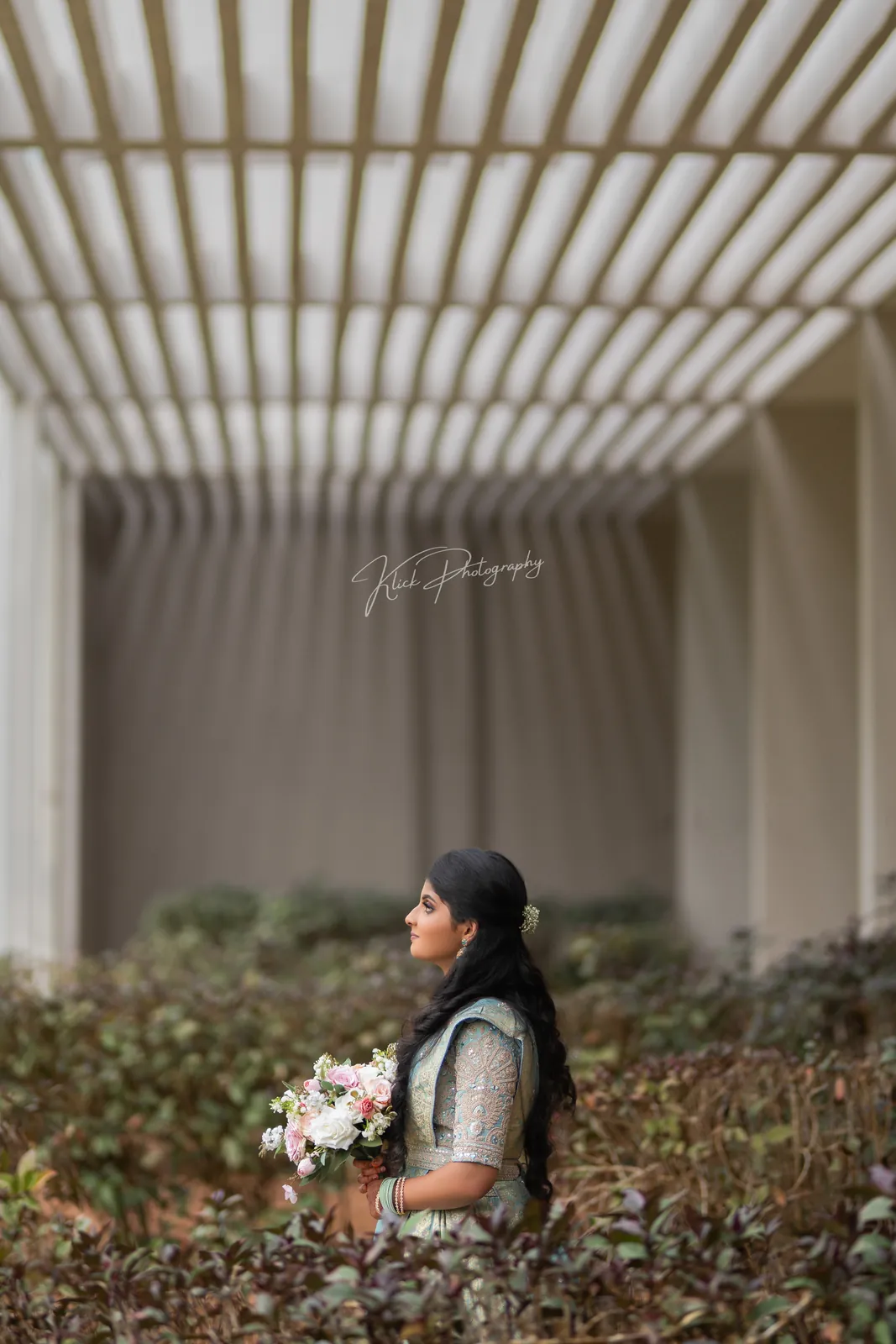 Bride with flowers standing in a bright colonnade