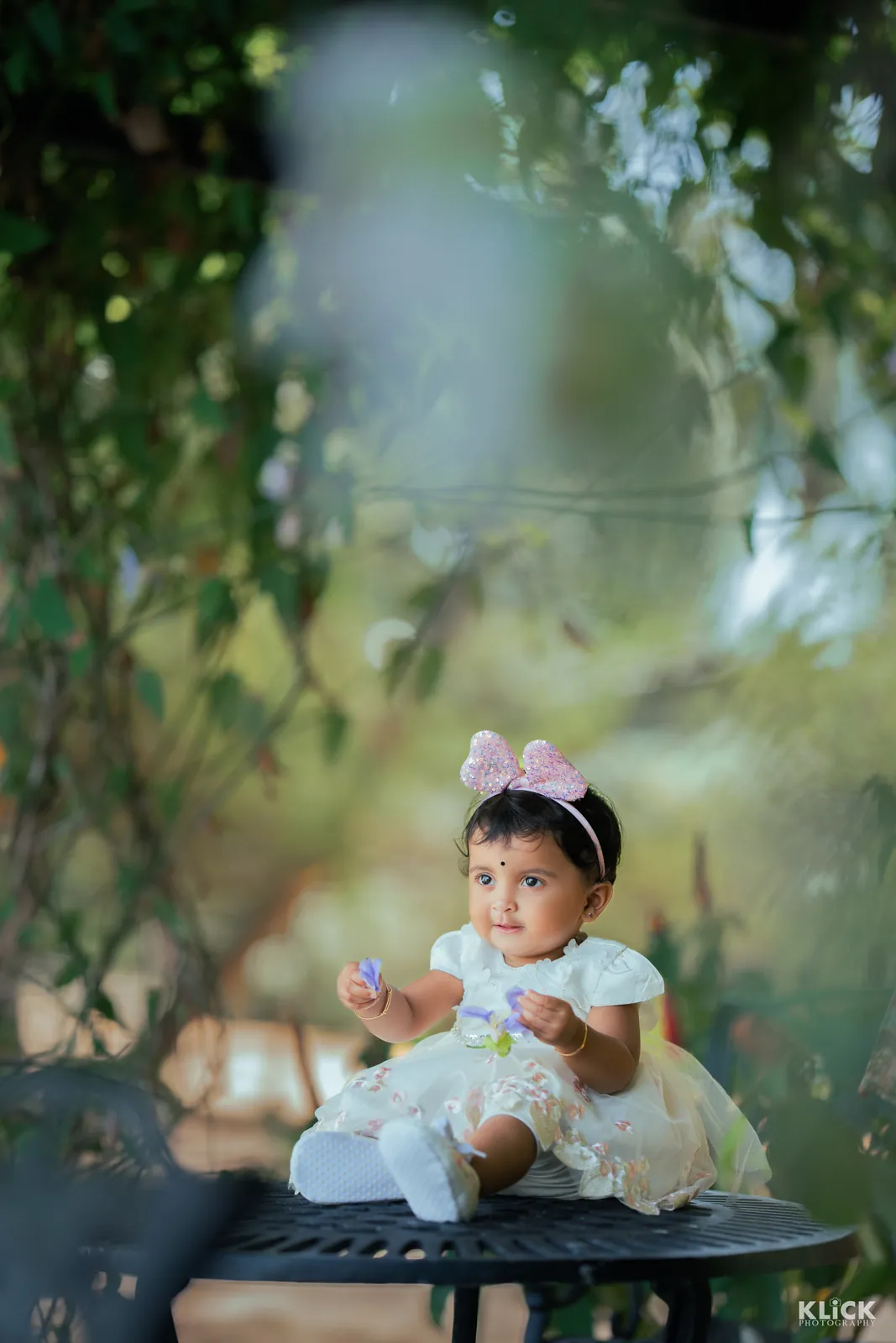 Baby girl seated among flowers during a family session