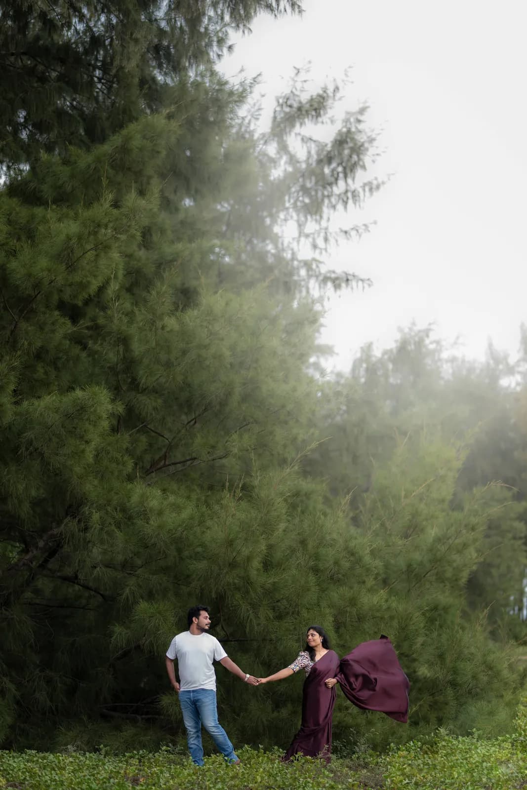 Couple holding hands on a misty forest path