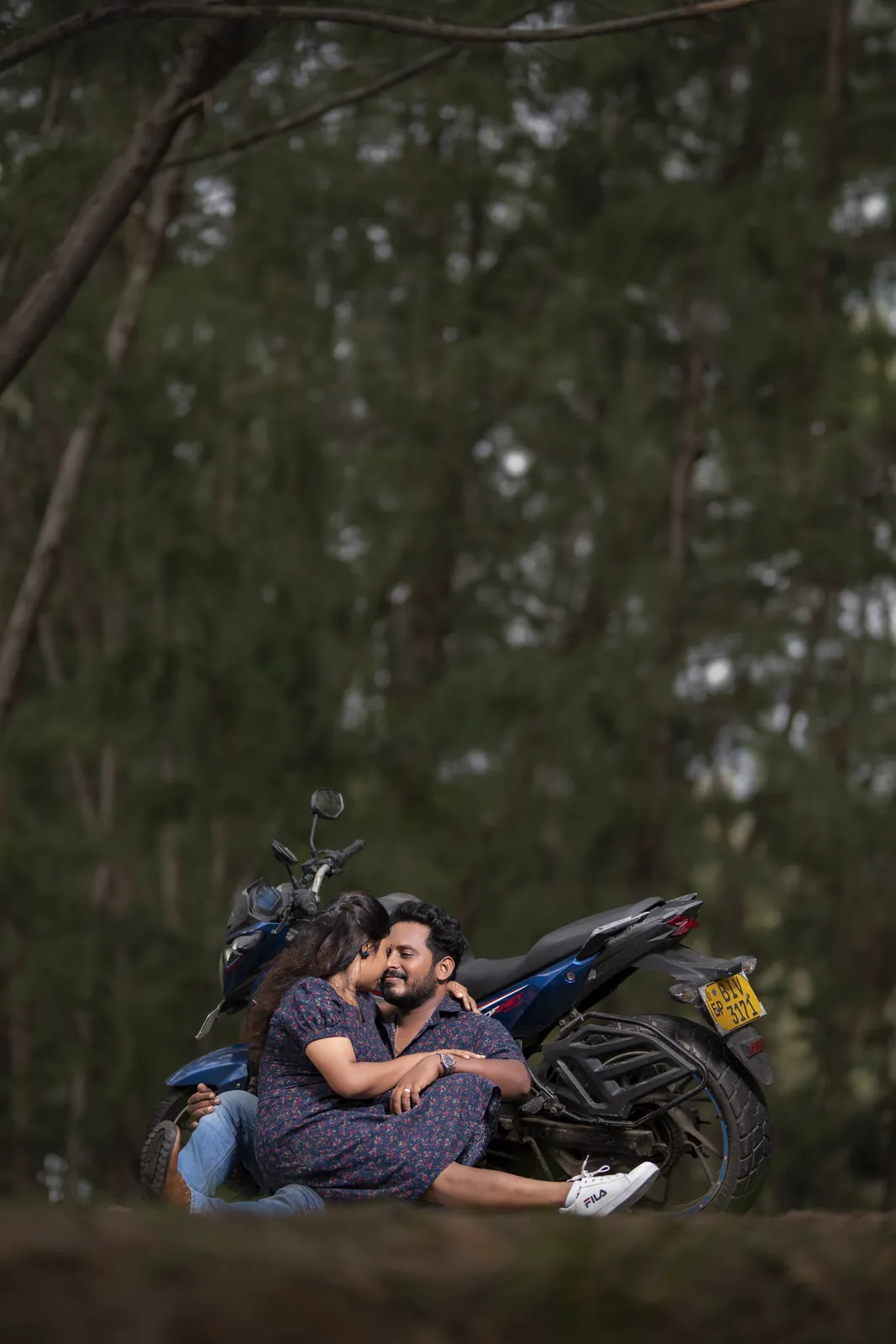 Couple resting on a motorbike under the trees
