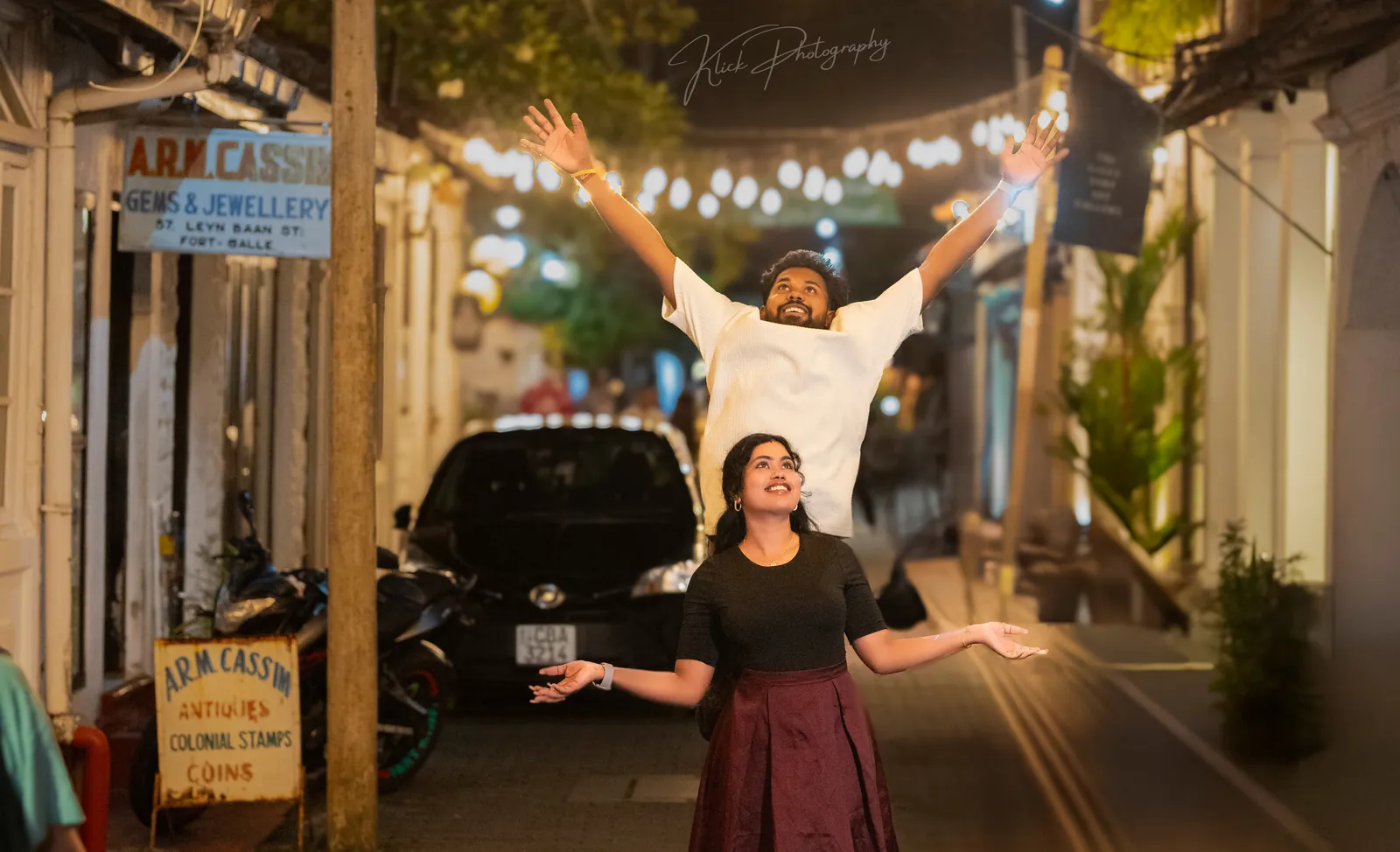 Couple celebrating on a street strung with lights
