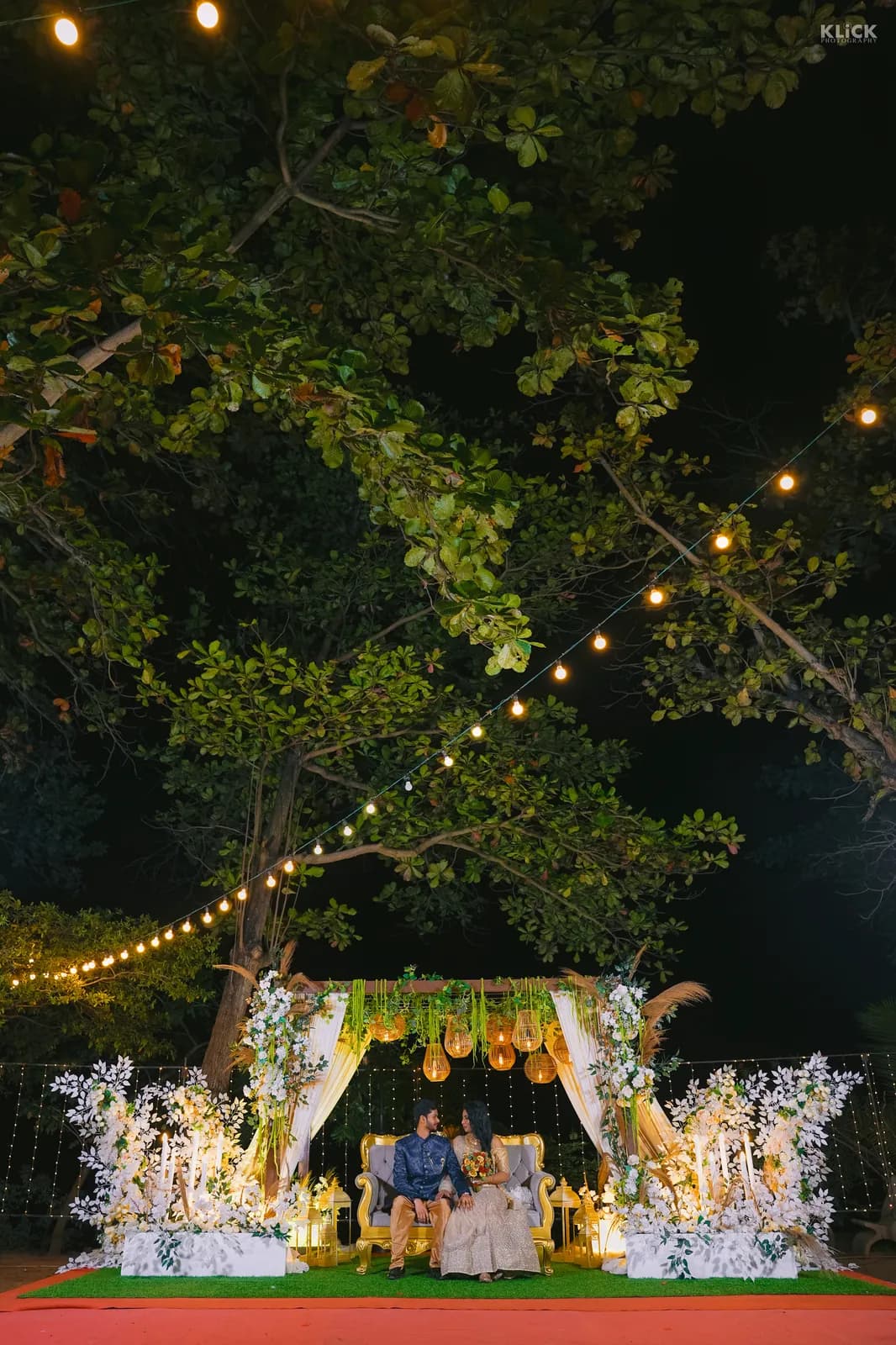 Outdoor wedding stage lit with festoon lights at night